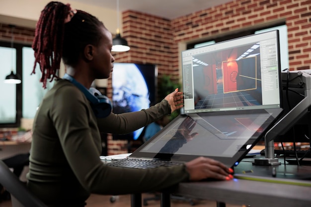 Creative game creator works with graphics for new level design while sitting at desk with two displays. Developing company employee working at computer with two monitors while editing environment.