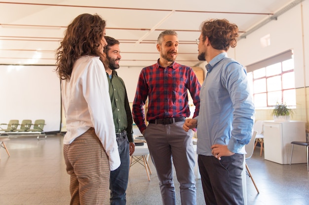 Creative group discussing ideas, standing in circle