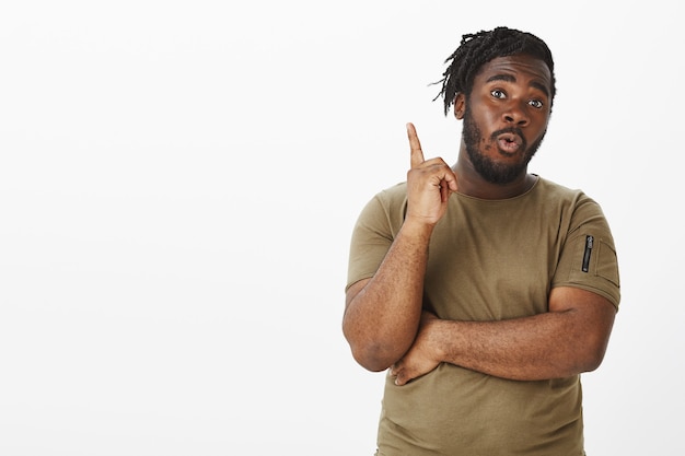 Creative guy in a brown t-shirt posing against the white wall