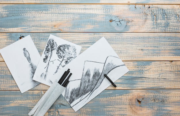 Free photo creative hand drawn sketches and charcoal sticks over wooden desk