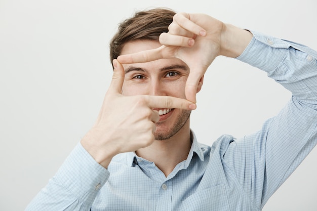 Free photo creative handsome man showing hand frames, capture moment