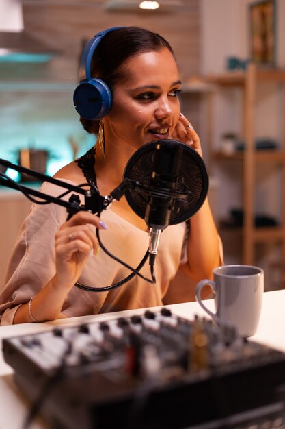 Creative influencer with headphones speaking with fans during live on social media using professional gear