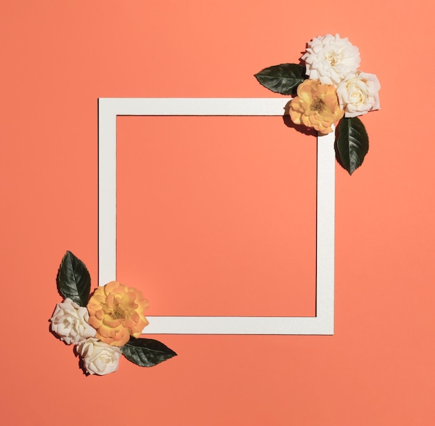 Creative layout made with spring flowers and white frame on pastel orange background