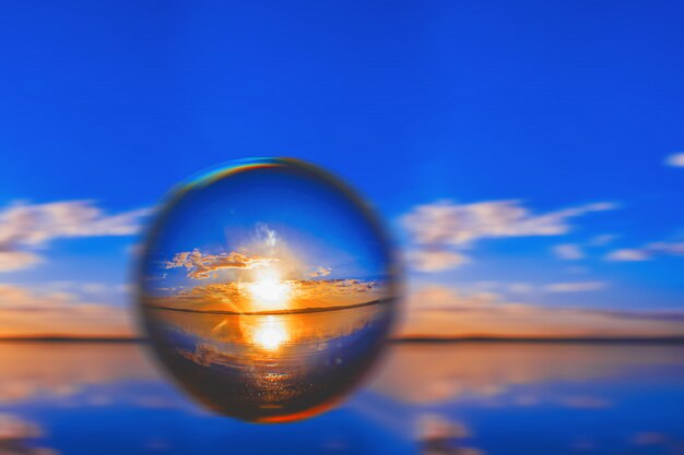 Creative lens ball photography of the sunlight on the horizon with clouds around in the blue sky