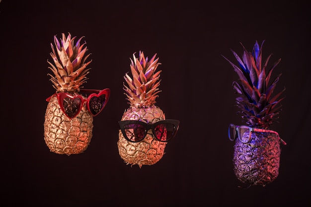 Foto gratuita ananas creativi con gli occhiali su uno sfondo nero