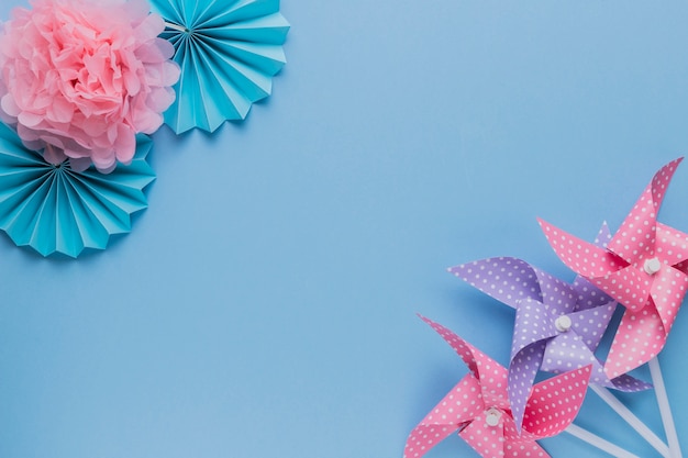 Creative pinwheel and beautiful paper flower at the corner of plain background