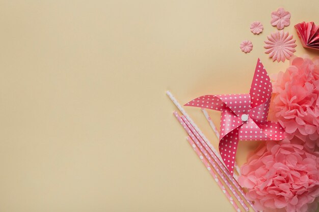 창조적 인 바람개비; 종이 꽃과 베이지 색 표면에 짚