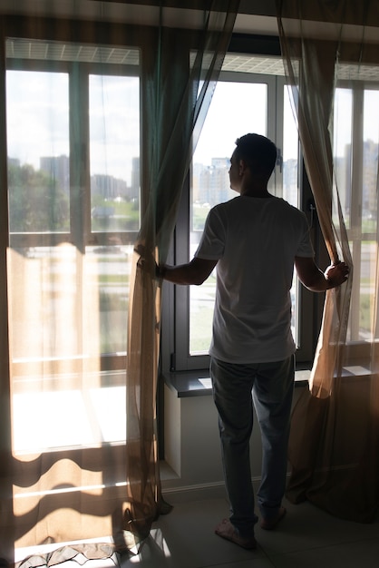 Free photo creative portrait of man with curtains and shadows from window