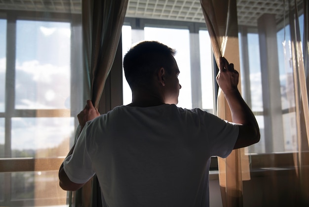 Free photo creative portrait of man with curtains and shadows from window