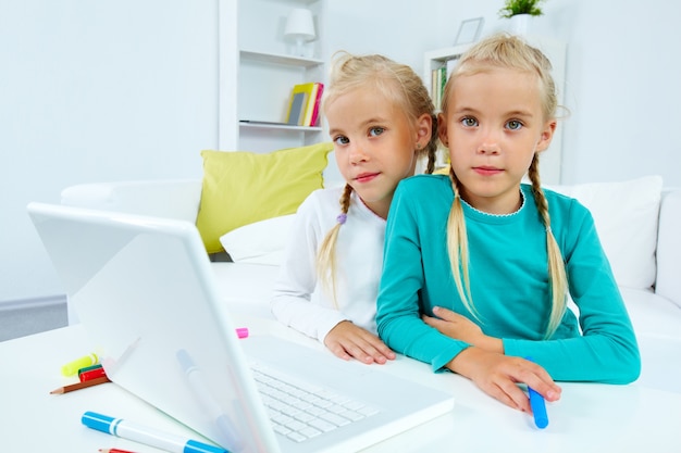 Free photo creative twins sitting with laptop