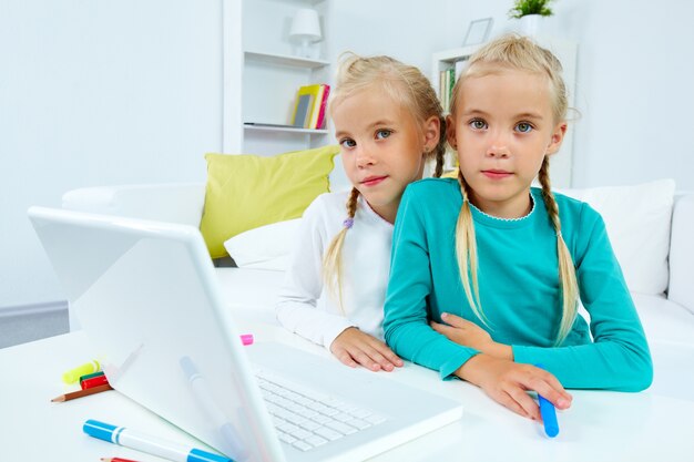 Creative twins sitting with laptop