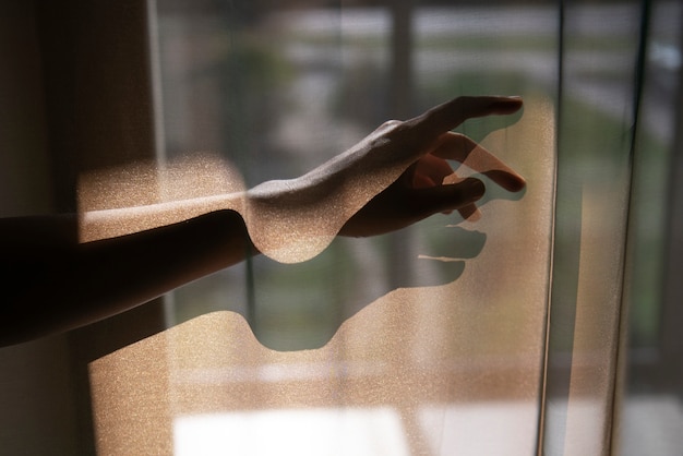 Free photo creative view of hands with curtains and shadows from window