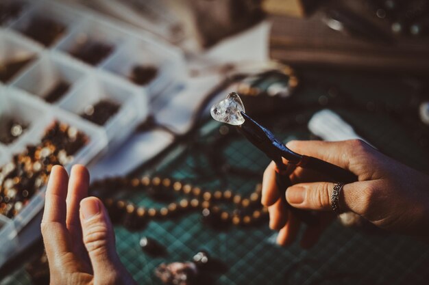 Creative woman is holding pliers and crystal clear quartz in it.