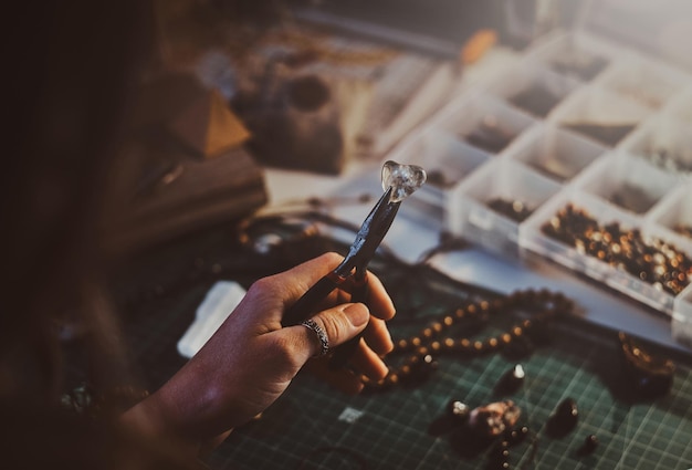 creative woman is holding pliers and crystal clear quartz in it.