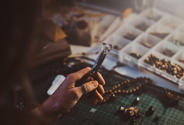 Creative woman is holding pliers and crystal clear quartz in it.