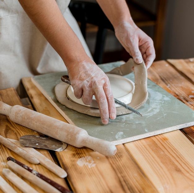 Творческая женщина делает глиняный горшок в своей мастерской