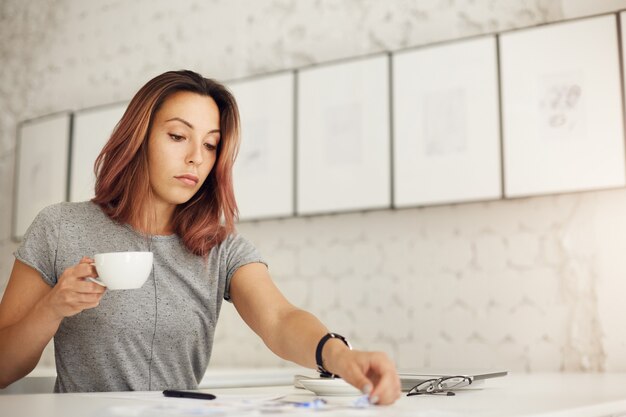 Creative worker doing her daily job drinking coffee resting from her overwhelming online life.