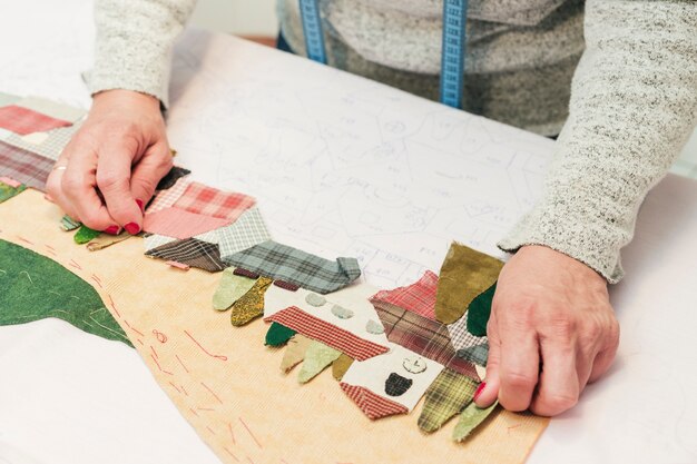 A creative young woman creating fabric patchwork scenery on paper