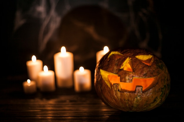 Creepy carved pumpkin and white candles