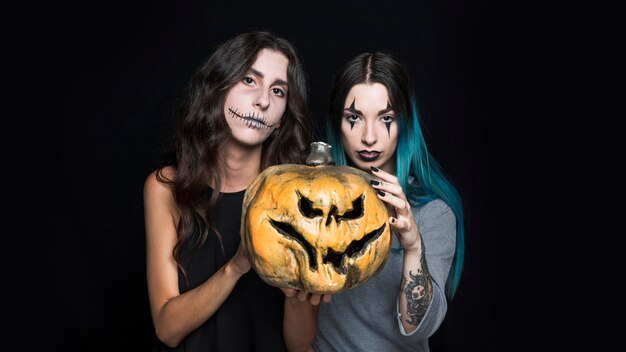 Creepy young women holding pumpkin