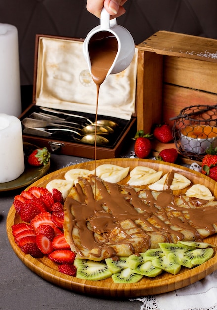 Crepe with chocolate sauce and sliced strawberries, kiwi and bananas