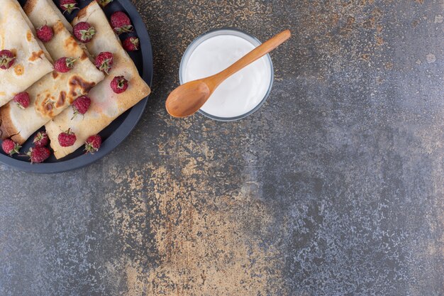 Crepes served with raspberries and a cup of sour cream