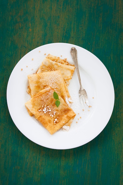 Free photo crepes with icing sugar and a fork