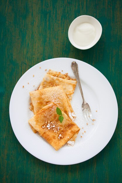 Crepes with icing sugar on a green background