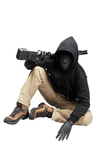 흰색 배경 위에 격리된 엽총을 들고 앉아 있는 숨겨진 마스크를 쓴 범죄자