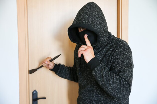 ドア​の​近く​に​バール​を​持った​犯罪者​。​強盗​が​家​に​侵入​。