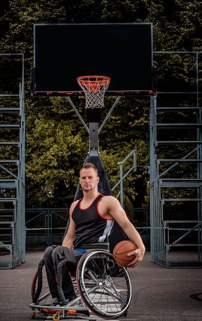 車椅子の不自由なバスケットボール選手は、開いたゲーム場でボールを保持します。