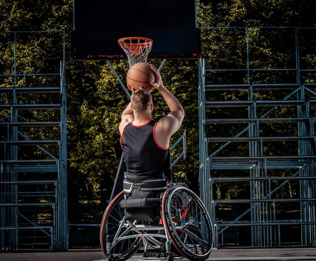 Cripple basketball player in a wheelchair plays on an open gaming ground.