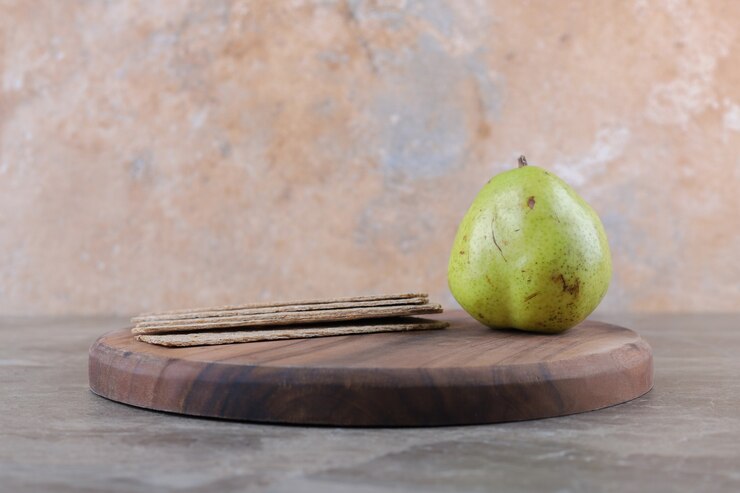 Free Photo crispbreads and pear on the board, on the marble surface