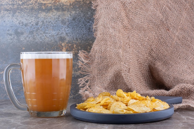 Free photo crispy chips on dark board with glass of beer. high quality photo