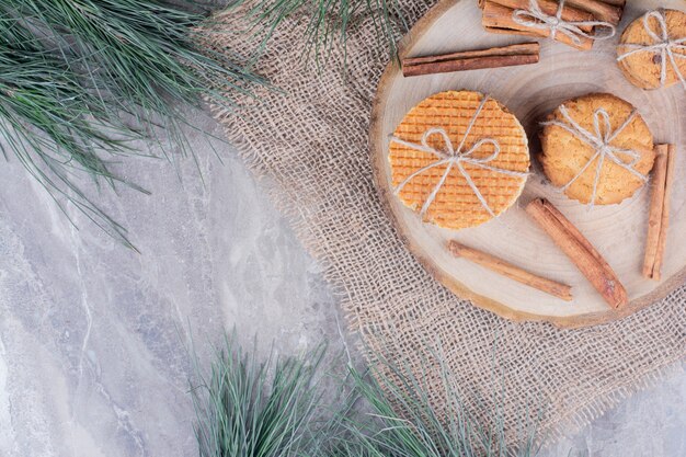 Crispy cookies on a wooden board with cinnamon sticks around