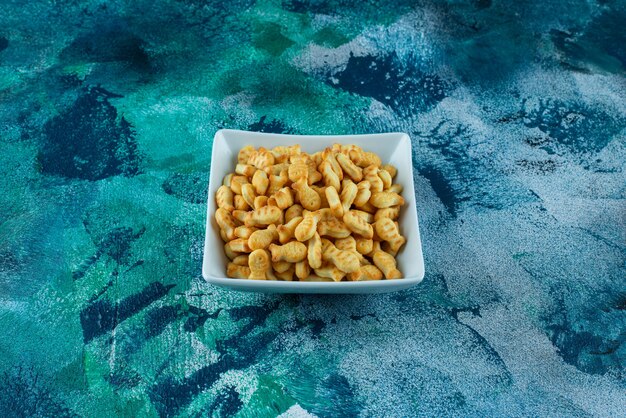 Crispy cracker fish in a bowl on blue. 