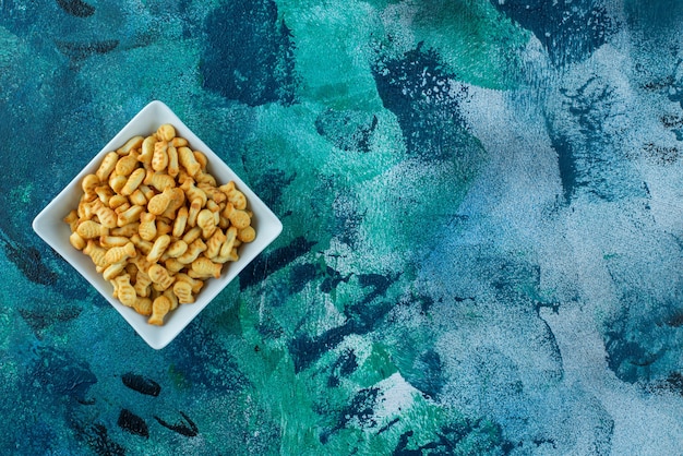 Free photo crispy cracker fish in a bowl on blue.