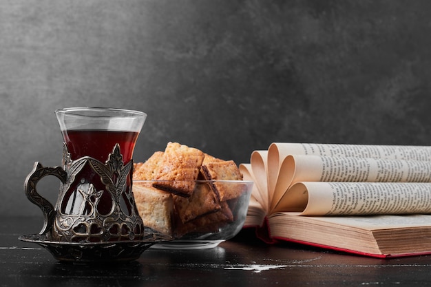 Crispy crackes in a glass cup on black background with a glass of tea.