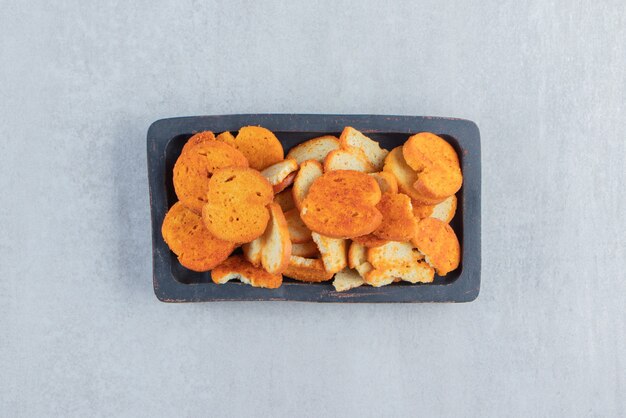 Crispy dried crumbs on black plate on stone.