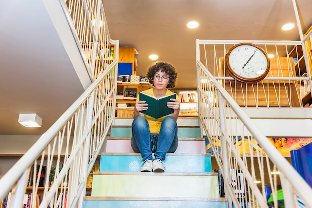 階段に座っている朗らかな女性の読書。