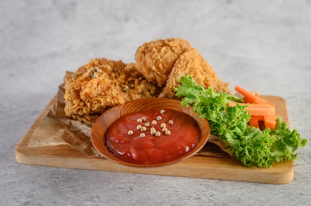 Crispy fried chicken on a cutting board with tomato sauce