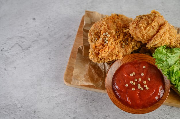 Crispy fried chicken on a cutting board with tomato sauce