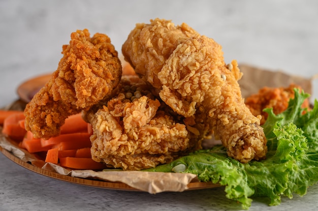 Crispy fried chicken on a plate with salad and carrot