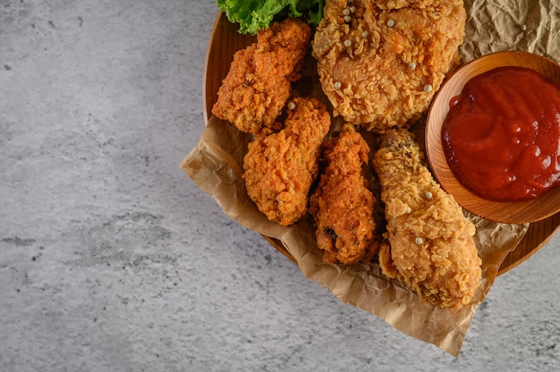 Crispy fried chicken on a wooden plate with tomato sauce
