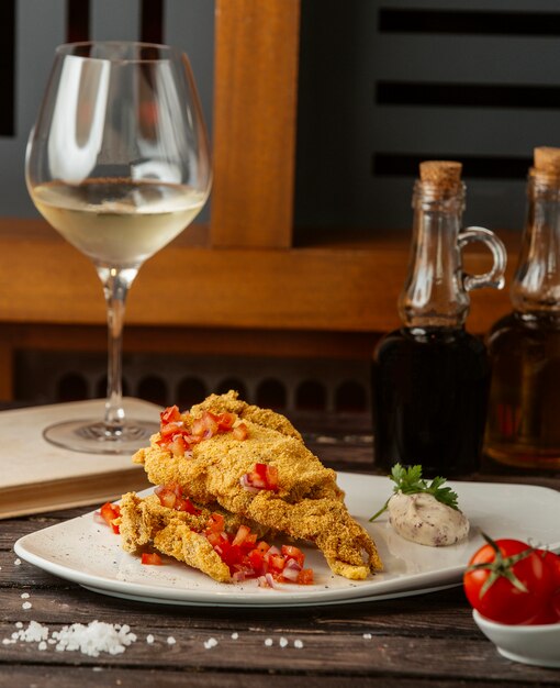 crispy fried fish garnished with tomato cubes, served with herb sauce