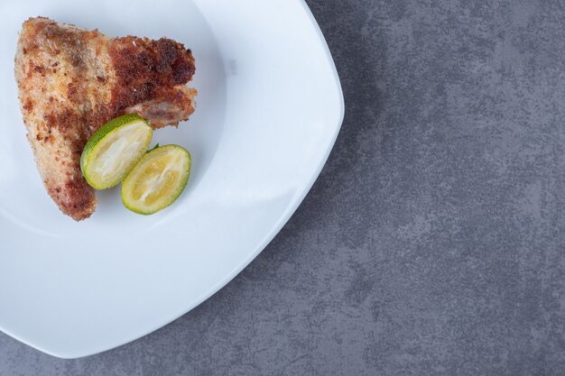 Crispy fried wing on white plate.