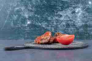 Free photo crispy fried wings and tomato on black board.