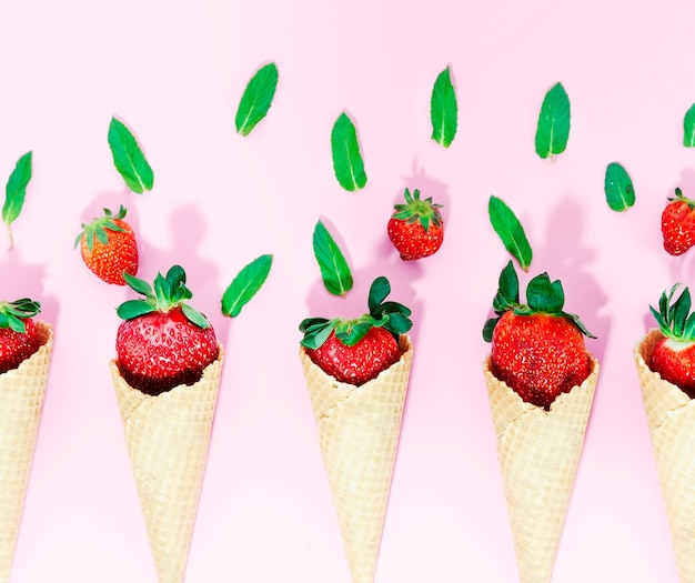 Crispy ice cream cones with strawberry on light surface