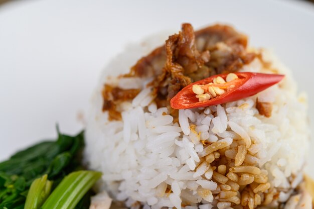 Crispy pork on a white plate topped with sauce and chili split in half.