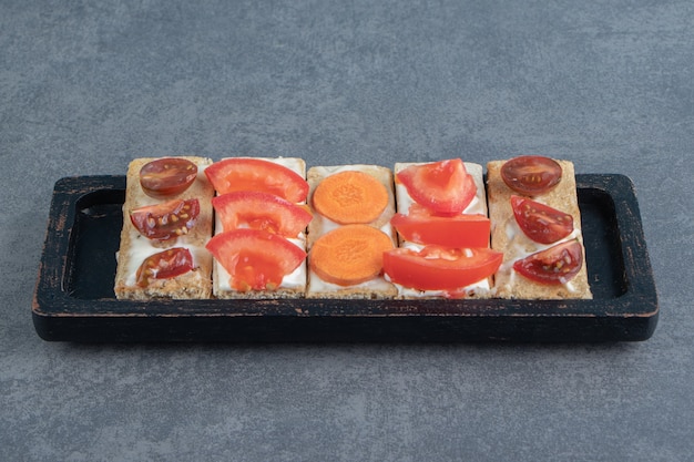 Crispy toasts with tomatoes on wooden board .